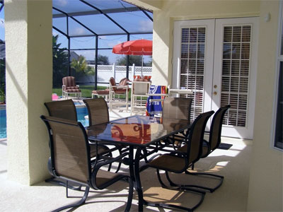 Dining table & chairs on pool deck under covered lanai